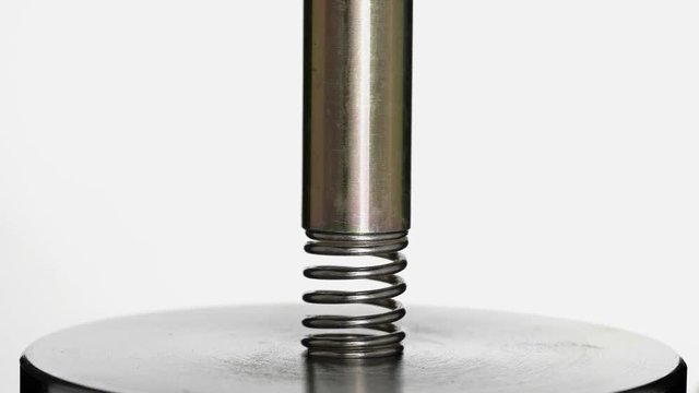 test of reliability of a spring, compression and decompression by a hydraulic press, close-up