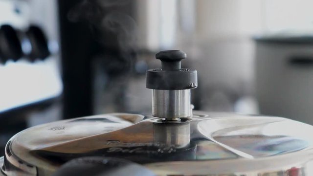 Close up of a pressure cooker whistle as the steam rushes out.