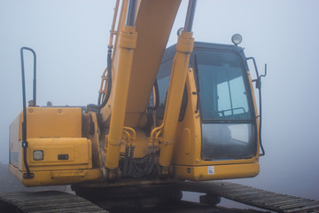 yellow excavator and foggy day