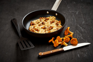 delicious scrambled eggs with chanterelles straight from the forest in a pan on a wooden kitchen table
