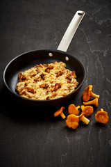 delicious scrambled eggs with chanterelles straight from the forest in a pan on a wooden kitchen table