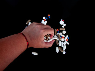 A person holding pills of different sizes, shapes and colors with his hand. Health concept