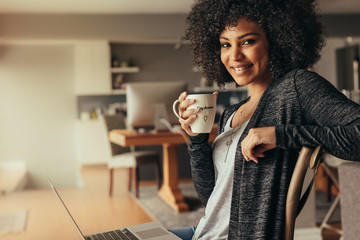 African woman taking coffee break while working from home