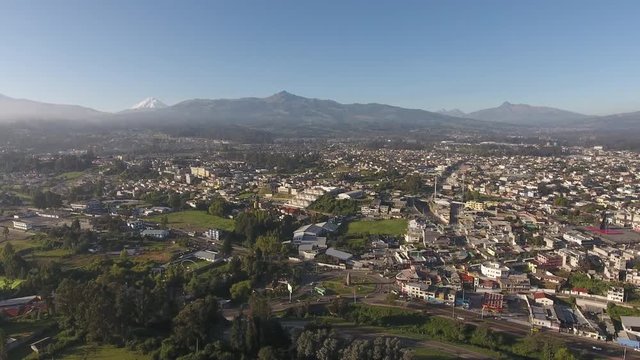 Aerial pan over Sangolqui, Ecuador. In the Inter-Andean valley near Quito, Ecuador. Many volcanoes visible in background, including snowcapped Cotopaxi. Pan starts with the Choclo roundabout