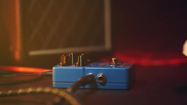 Close up of guitar player foot pressing pedal. Musician uses music effect loop machine. Man in trendy sneakers, his foot playing at stage during concert. Macro view.
