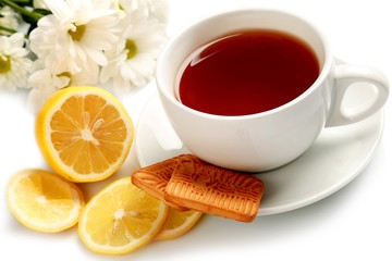 Hot drink with a lemon, cookies and flowers