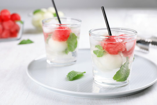 Glasses with tasty melon and watermelon ball drinks on plate