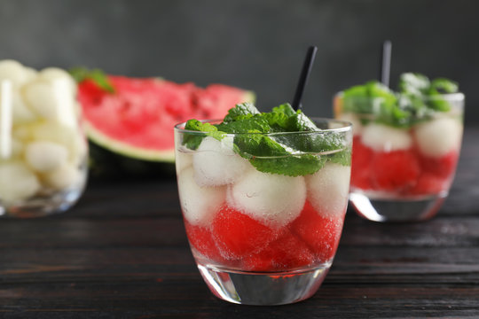Glass with tasty melon and watermelon ball drink on dark table