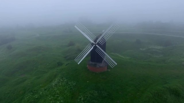 Rotating aerial footage of the Pistone windmill on a foggy day