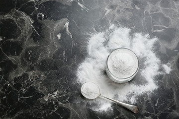 Jar and spoon with baking soda on grey background, top view. Space for text