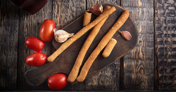 grissini, tomatoes and garlic on the wooden cut board
