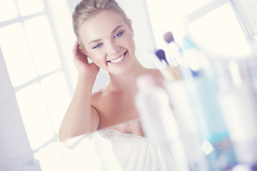 Young woman in bathrobe looking in bathroom mirror
