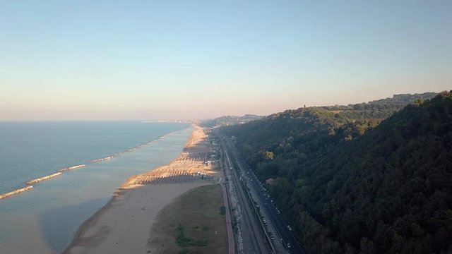 aerial view of mountain with national road, railway line and moving train, cycle path, beach and sea