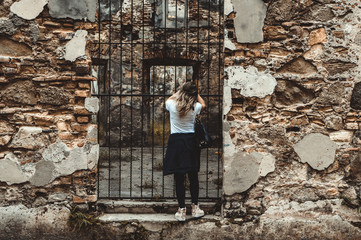 Woman taking picture with cell phone from the ruins of an old house