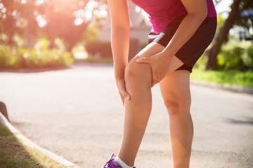 Runner sport knee injury. Woman in knee pain while running in the garden.