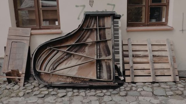A wide shot of an old broken grand piano placed outside cafe