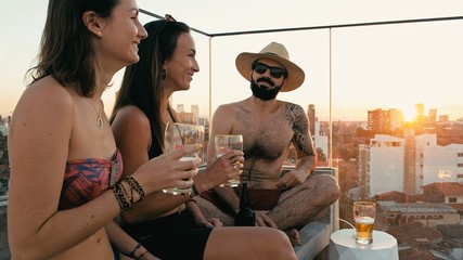 young woman and man people enjoying a beer and the company at a rooftop bar above the city with beautiful view with a cute pet dog