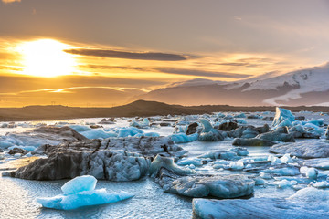 Sunset at the iceberg lagoon in Iceland, snow cape mountains in the background, cloudy sky