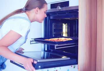 Happy young woman cooking pizza at home
