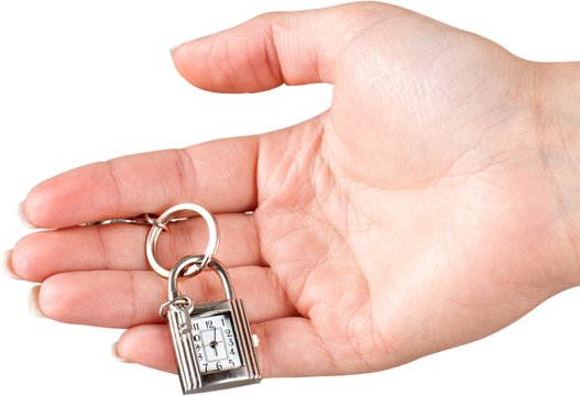 Female hand holding keychain with little clock and key isolated