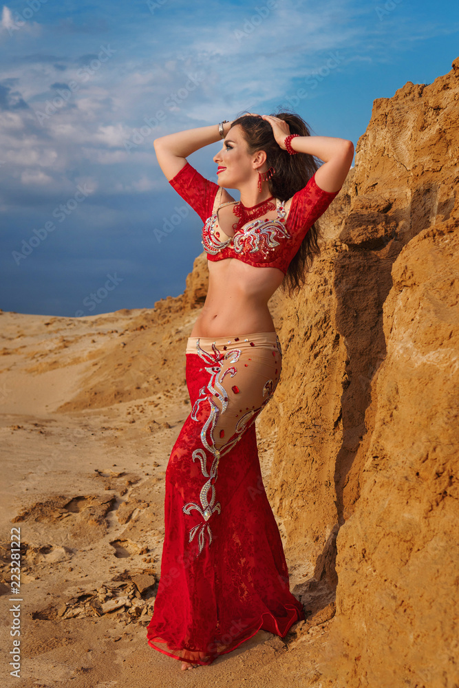 Wall mural oriental beauty dancing sensual belly dance outdoors. arab dance of seduction. a girl in a red dress