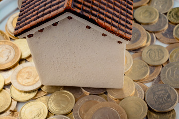 Turkish Lira coins by the side of a model house