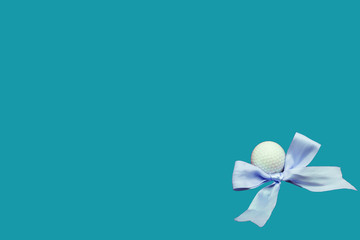Golf ball with blue ribbon on blue background idea for boy baby shower for golfer