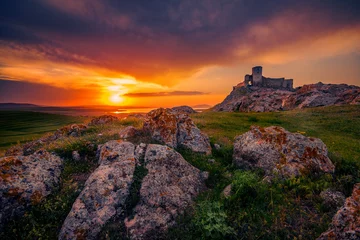 Brushed aluminium prints Rudnes Old ruined citadel on a rocky hill shot at sunset with some rocks in the foreground