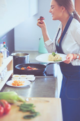 Young woman standing by the stove in the kitchen