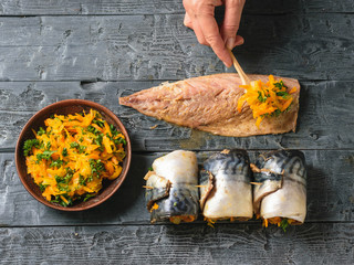 Woman puts a spoon of vegetable mixture on the carcass of fish for rolls. The view from the top....