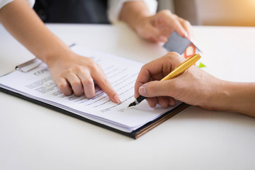 Estate agent pointing finger on document showing where to sign. Signing a paper document for buying house.Real estate, home loan and insurance concept