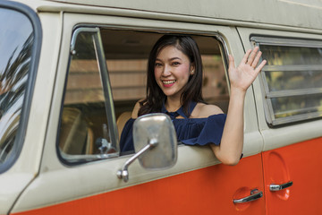 happy woman vintage window of old car and raising her hand