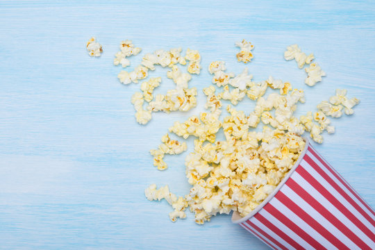 a glass of popcorn, scattered on a blue background