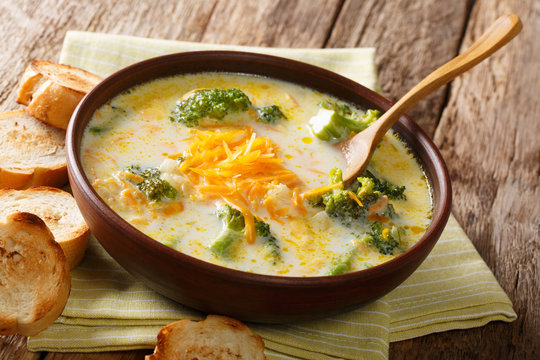 Delicious cheesy broccoli soup with vegetables in a bowl with toast close-up. horizontal