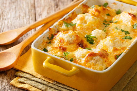 Hot appetizer: baked cauliflower with cheese cheddar close-up in a baking dish. horizontal