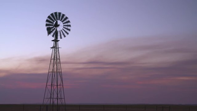 Silhouette of a windmill pumping water for cattle at Colorado prairie