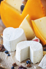 many different kinds of cheese with figs and nuts on an old wooden table in rustic style