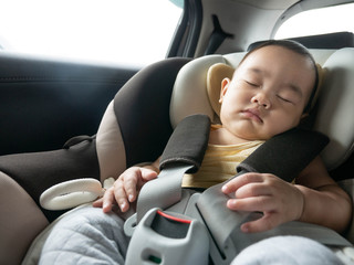 baby boy is sleeping in  safety seat, car seat.