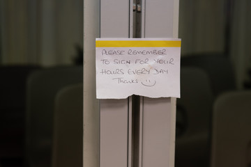 Sticky note reminding workers to fill in their work hours.