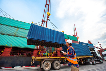 container unit being lifting loading by the shipâ€™s crane from the trailer delivery to the port terminal, the services of logistics and transport shipment to worldwide global
