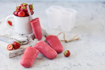 Homemade strawberry ice cream on wooden board over white background