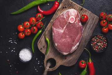 Raw fresh cross cut veal shank and ingredients for Osso Buco cooking on black background