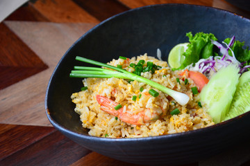 fried rice with shrimp and egg in ceramic bowl on wooden table background (selective focus)
