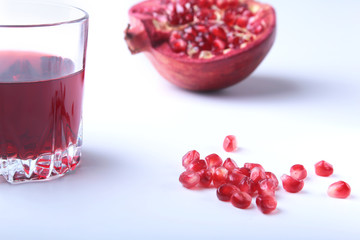 Glass with pomegranate juice Pomegranate seeds and Beautiful ripe pomegranate on white background with place for copy space.