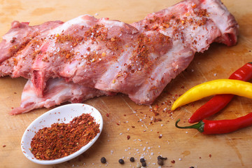 Fototapeta premium Raw Ribs on a rustic cutting board with salt, pepper and grinder for spices . copy space. Top View.