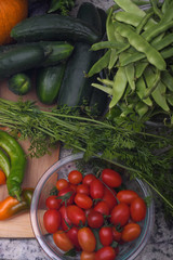Flat lay photo of a day's harvest, including pumpkin, cucumber, green beans, carrot tops, peppers, tomatoes
