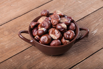Chestnuts in a clay bowl on the old wooden background