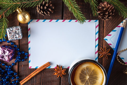 Christmas and New Year holidays. Spruce branch, cinnamon, anisee tree, cones, Christmas decorations, letter to Santa Claus and hot tea with lemon on a wooden background. Merry Christmas. Copy space