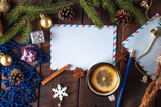 Christmas and New Year holidays. Spruce branch, cinnamon, anisee tree, cones, Christmas decorations, letter to Santa Claus and hot tea with lemon on a wooden background. Merry Christmas. Copy space