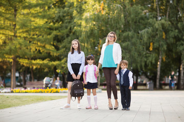 Children siblings and Mother holding hands going to school